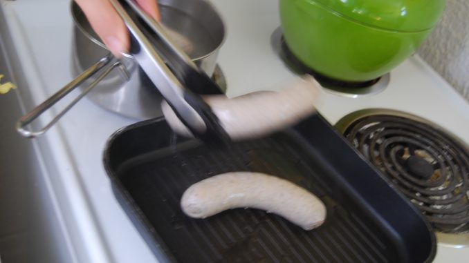 Saucisse transférer d'un chaudron à une poêle pour être griller.